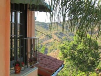 A balcony with a view of rolling hills and greenery.