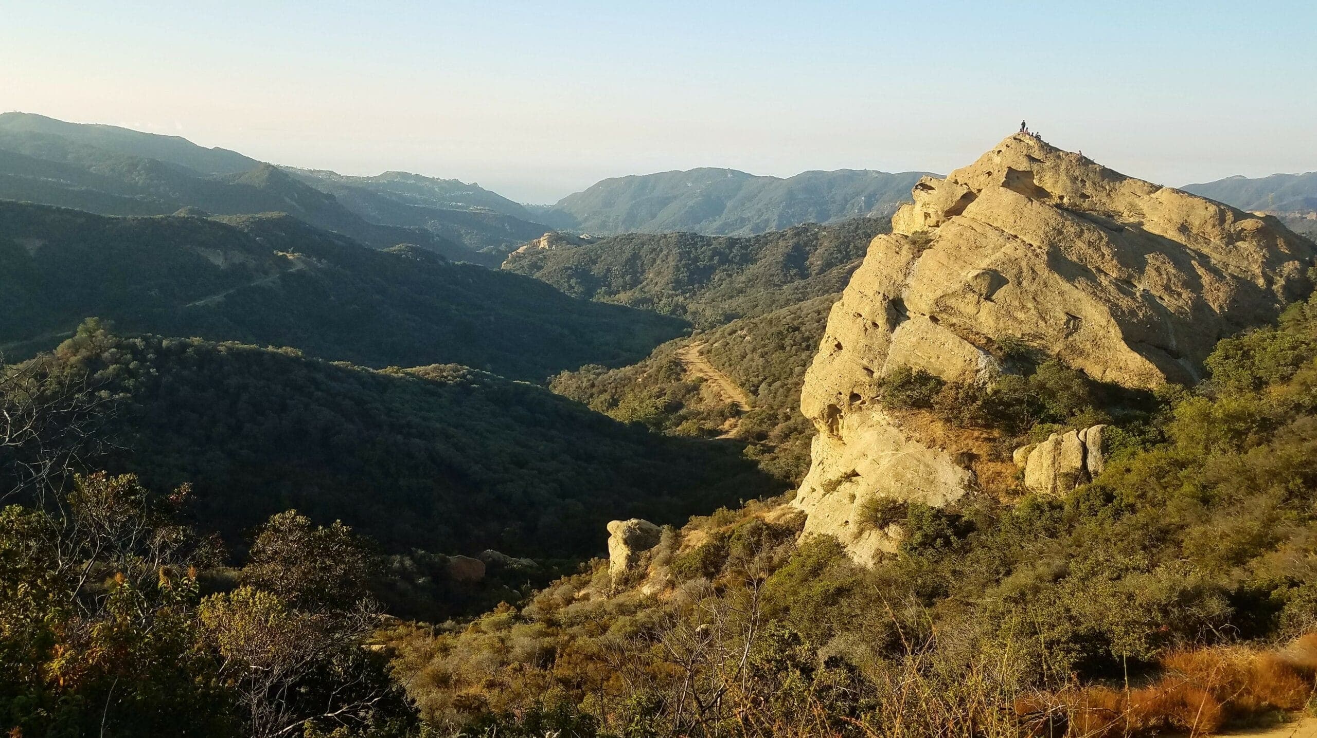 A scenic view of a rocky peak surrounded by rolling hills and valleys in the distance. A scenic view of a rocky peak surrounded by rolling hills and valleys in the distance.