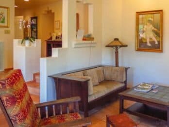 A cozy living room featuring a wooden sofa, a coffee table, and a decorative lamp, with artwork on the wall.